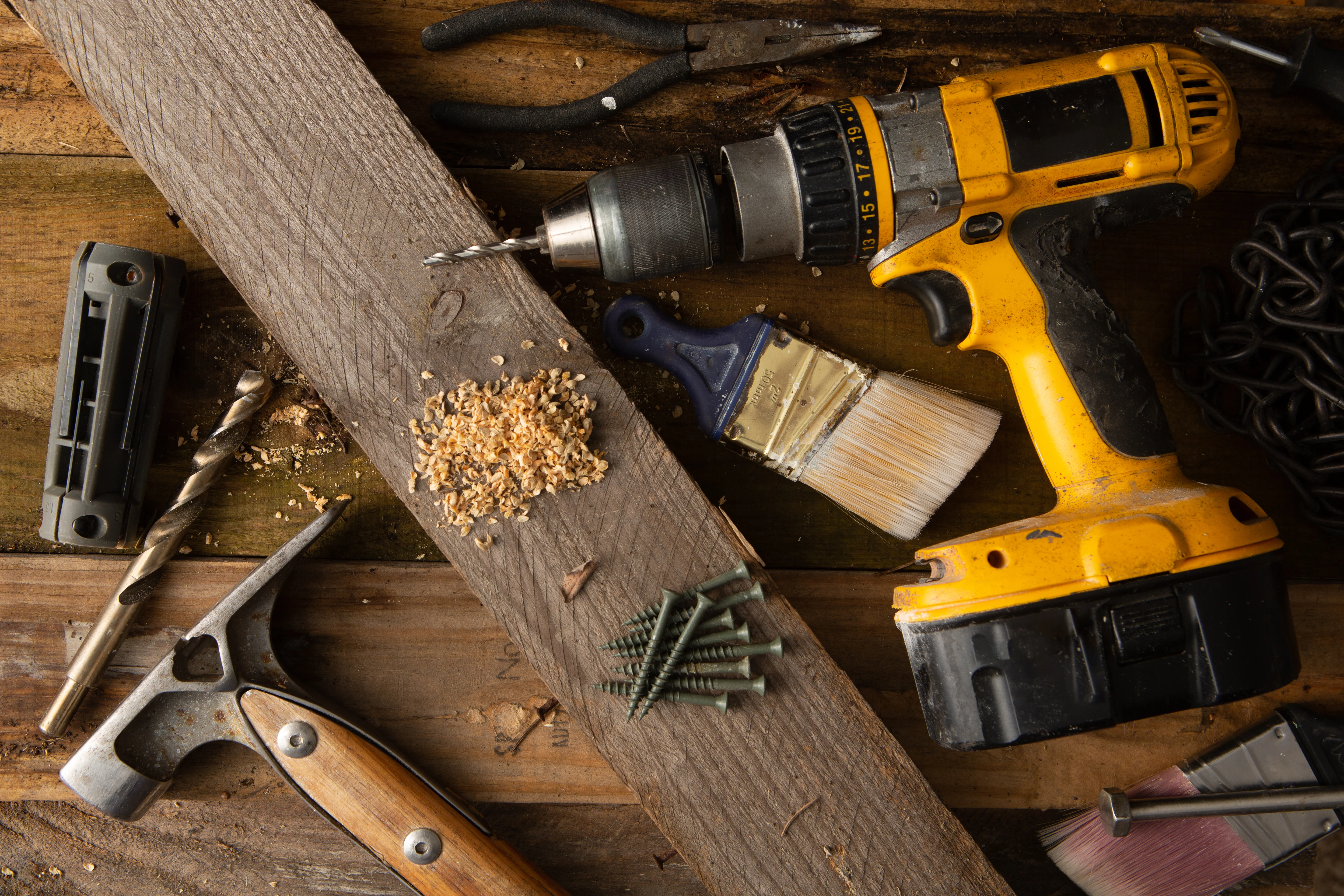 Professional handyman tools including drill, hammer, paintbrush and screws on wooden workbench - Coastal Craft Handyman Services South Florida